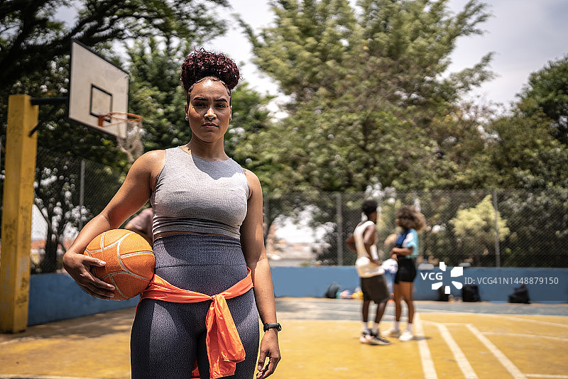 一个年轻女子在体育场上抱着一个篮球的肖像图片素材