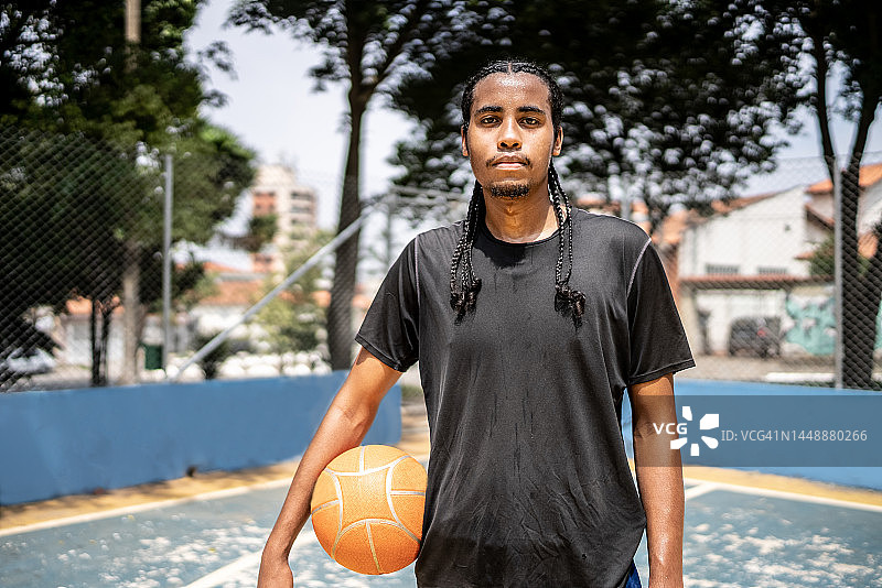 一个年轻人在运动场上抱着一个篮球的肖像图片素材