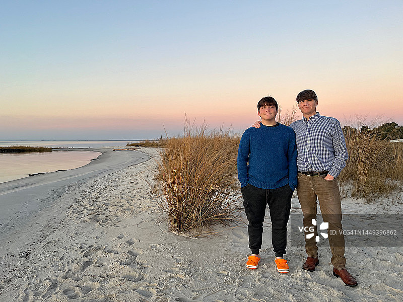 父亲和他的儿子在切萨皮克湾东岸享受感恩节的日落。丹吉尔的声音。图片素材