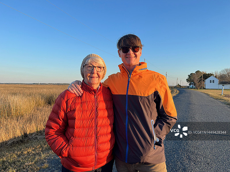 一位年长的妇女和她已成年的儿子走在一条乡间小路上，眺望着东海岸的一片沼泽。丹吉尔的声音。切萨皮克湾。图片素材