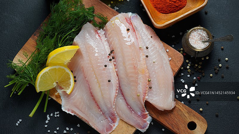 新鲜的红罗非鱼切片，配以香草、香料和柠檬作牛排或沙拉图片素材
