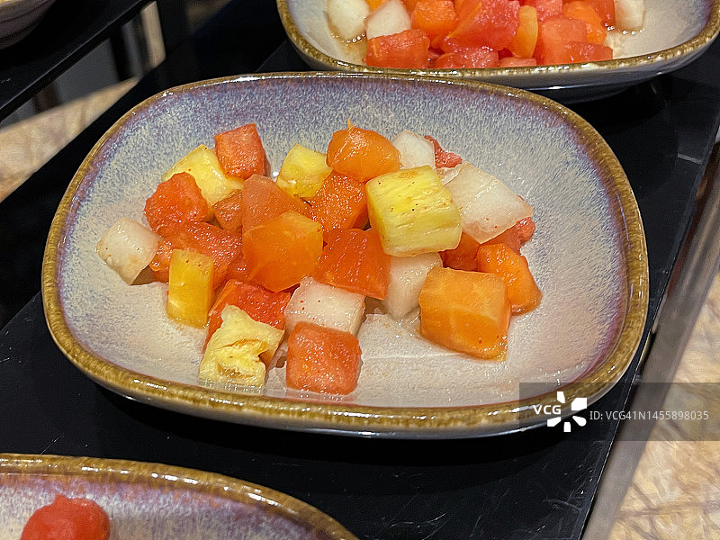 酒店自助早餐的特写图像，展示了成熟的菠萝丁，蜜瓜和木瓜(木瓜)水果沙拉，高视图，重点在前景图片素材