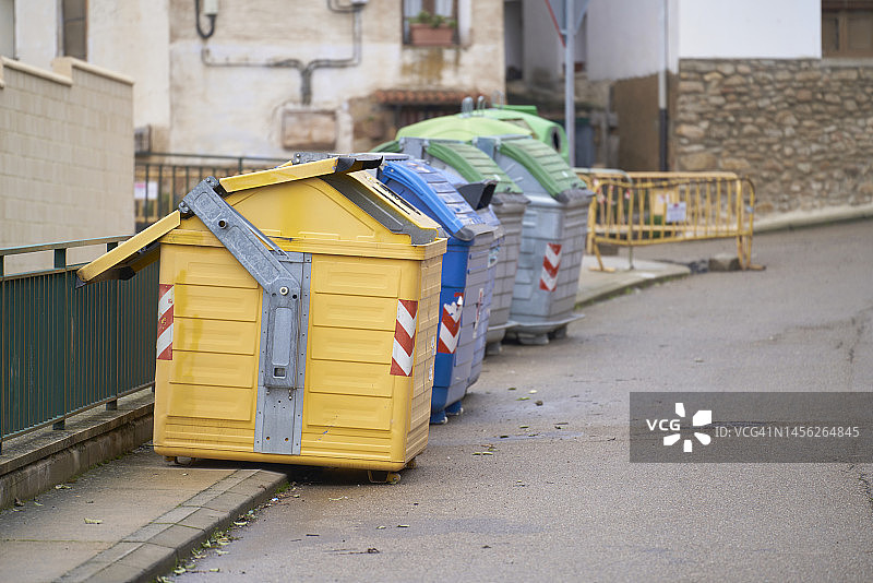 各种颜色的垃圾桶一个接一个地排在街上，从侧面看不见周围的人图片素材