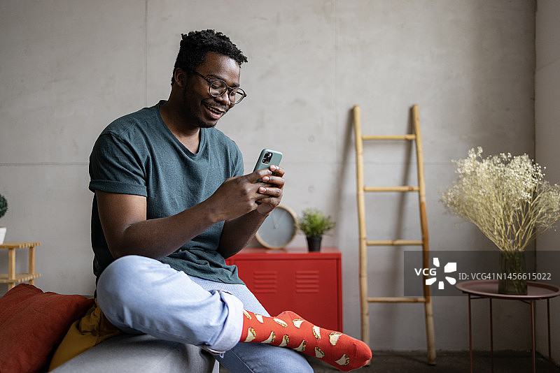 快乐的非裔美国人在家里使用智能手机图片素材