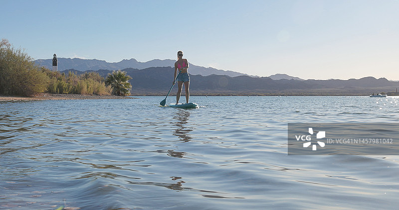 雌性桨板选手(SUP)在平静的湖面上出发图片素材