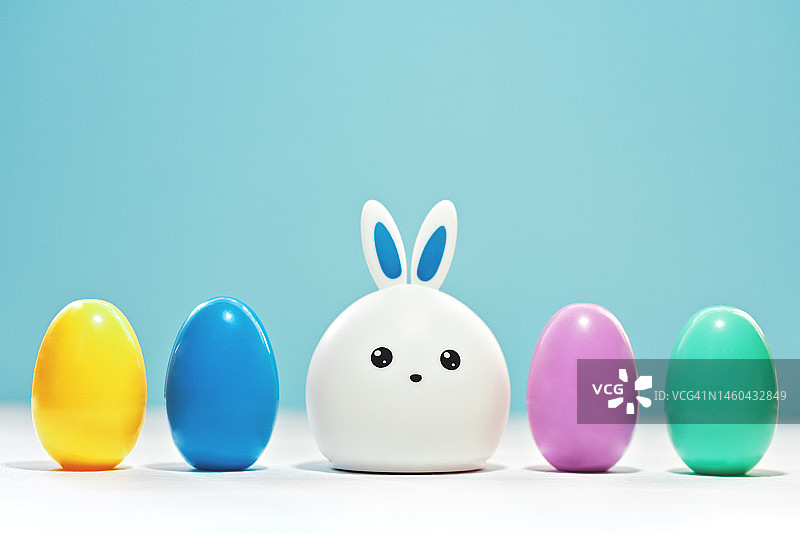 复活节快乐的概念。颜色鸡蛋和兔子的潮流粉彩蓝色背景。图片素材