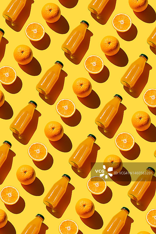 色彩鲜艳的鲜榨橙汁瓶子，新鲜的原料橙在黄色背景上。超级食品，健康食品，饮料，饮食和排毒概念。平铺，俯视图图片素材