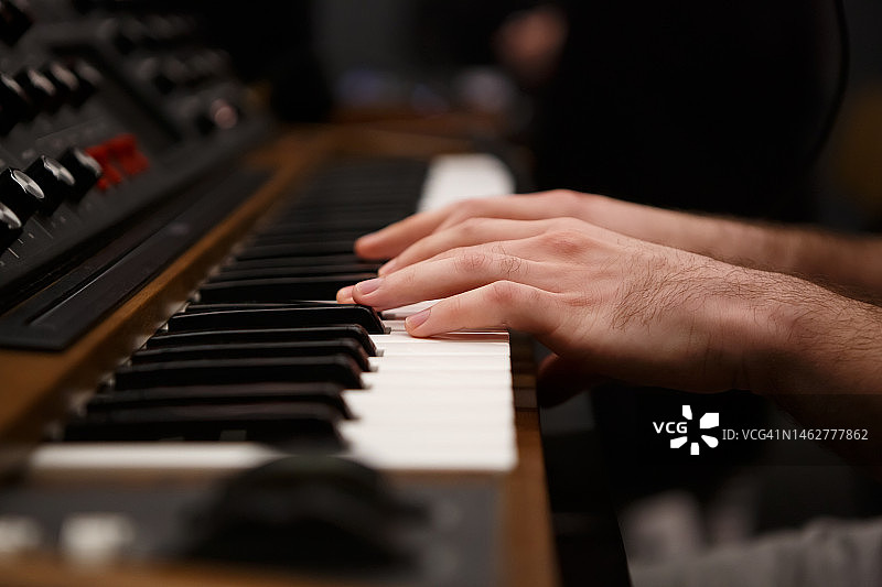 钢琴家的手在合成器上演奏音乐。专业的合成设备键盘在近距离图片素材