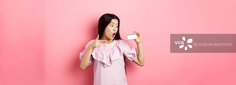 兴奋的亚洲妇女指着和显示塑料信用卡，喘息图片素材