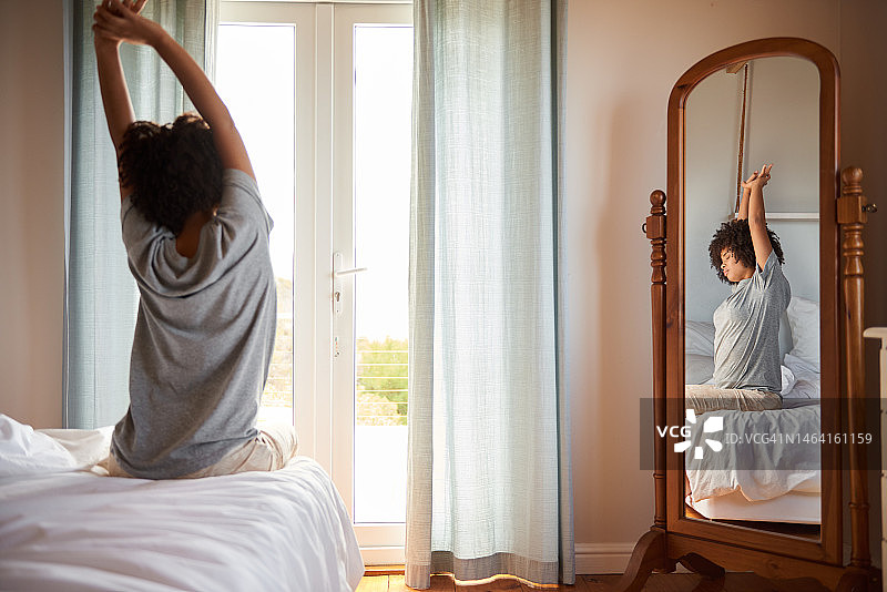 年轻的非洲女人在她的卧室里醒来，伸展身体图片素材