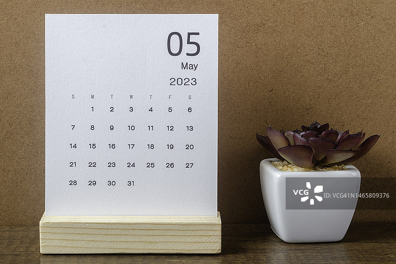 日历桌2023:五月是组织者计划和截止日期的月份，在牛皮纸背景下放置室内植物。图片素材