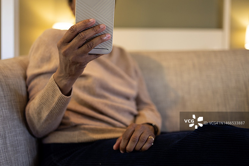 黑人妇女在沙发上休息时使用智能手机图片素材