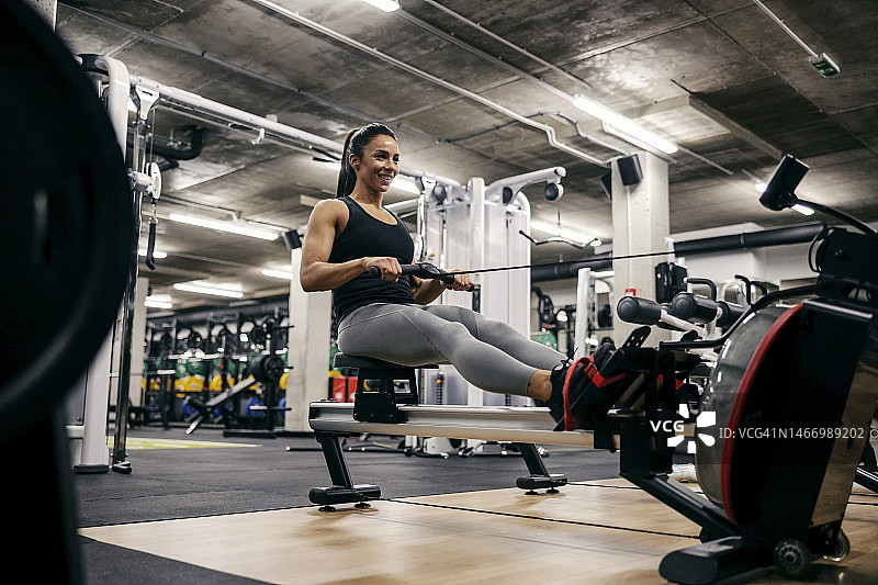 一位强壮健康的女运动员正在健身房的划船机上锻炼。图片素材