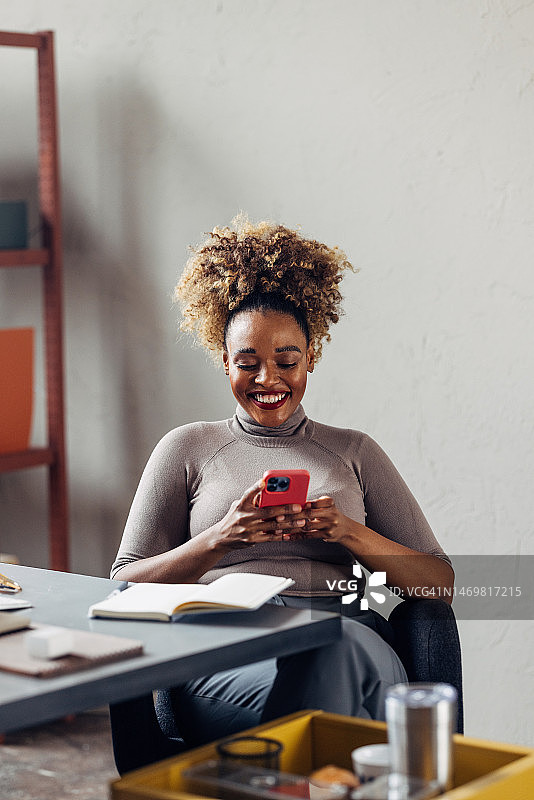 一个金发卷发的快乐美丽的女商人在她的手机上发短信图片素材