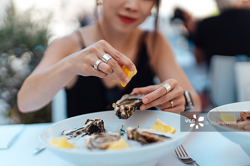 特写的女人的手挤压柠檬汁在新鲜的牡蛎图片素材