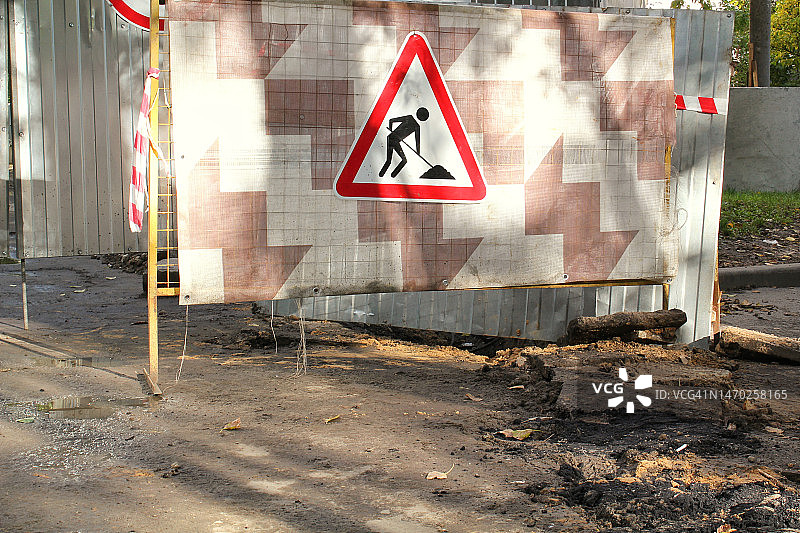 施工道路三角形标志金属围栏背景。铺设新沥青路面的准备工作。图片素材