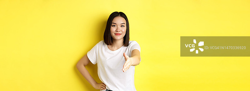 自信的亚洲妇女在白色t恤，伸出手握手图片素材