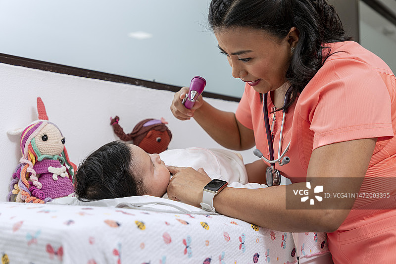 儿科医生在她的诊所里用灯检查婴儿的口腔。图片素材