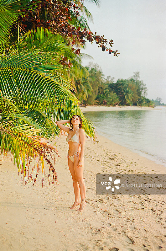 身着泳装的女子走在田园诗般的热带海滩上图片素材