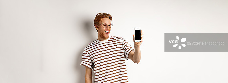 技术和电子商务概念快乐的红头发戴眼镜的年轻人图片素材