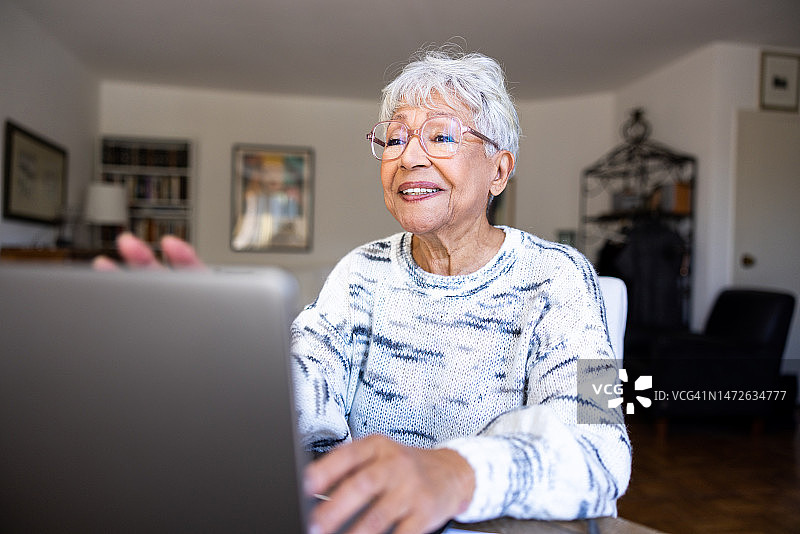 老年妇女在家里使用笔记本电脑图片素材