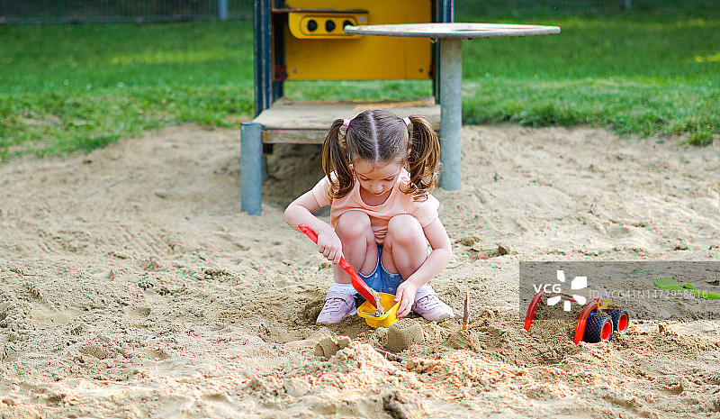 美丽的婴儿在阳光明媚的温暖的夏日玩-可爱的蹒跚学步的女孩在户外操场上玩沙子图片素材