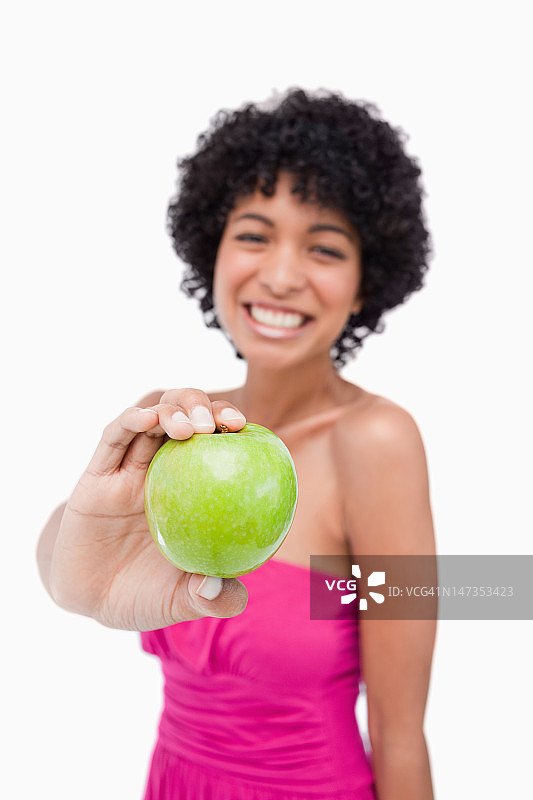 美丽的绿色苹果由一个年轻的女性在白色的背景图片素材