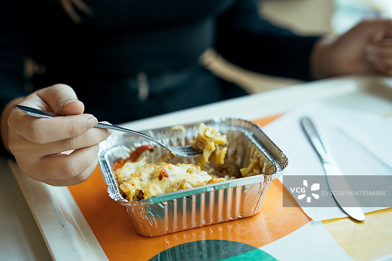 用铝箔制成的饭盒，里面有加热过的食物，可以随时食用。在餐厅休息吃午饭。咖啡装在托盘上的白色杯子里。零废物概念图片素材
