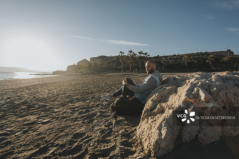 坐在海滩岩石旁沉思的人图片素材