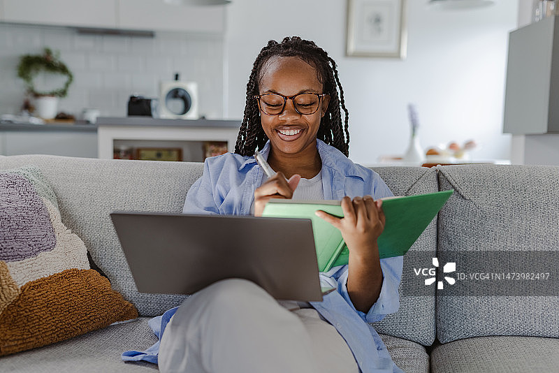 快乐的非裔美国妇女使用笔记本电脑和在家听在线课程图片素材