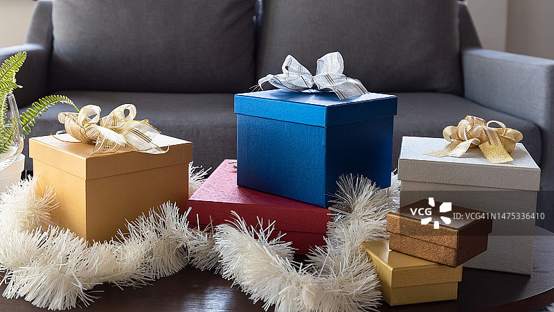 美丽的圣诞礼盒包裹在彩色的纸带蝴蝶结在客厅的桌子上，克拉约瓦，罗马尼亚图片素材