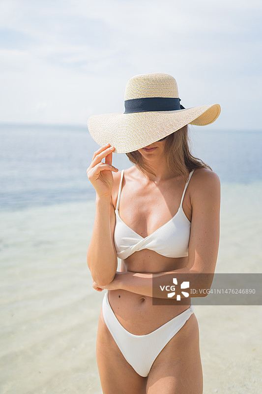 年轻女子在海滩上戴太阳帽图片素材