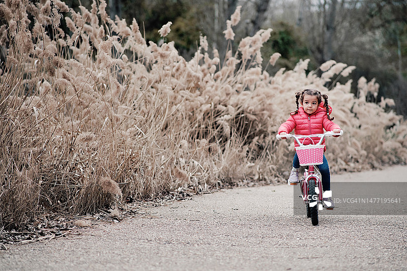 小女孩沿着小巷骑自行车图片素材