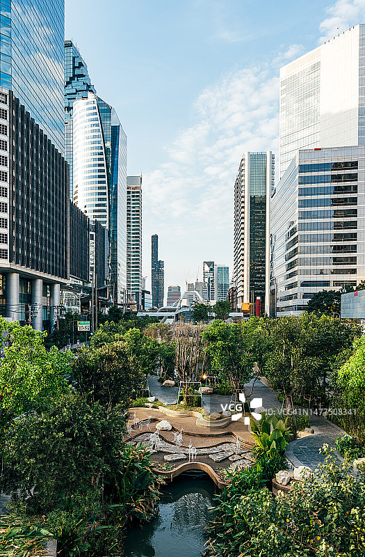 泰国曼谷的钟农西运河公园，清新的绿色植物被现代的未来主义摩天大楼包围图片素材