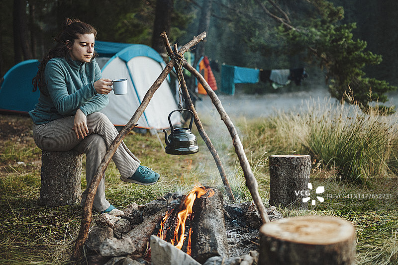 一个年轻的女人在露营度假时喝着早上的咖啡。图片素材