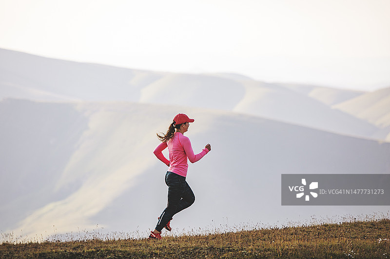 年轻的成年女子在日落时在山上跑步图片素材