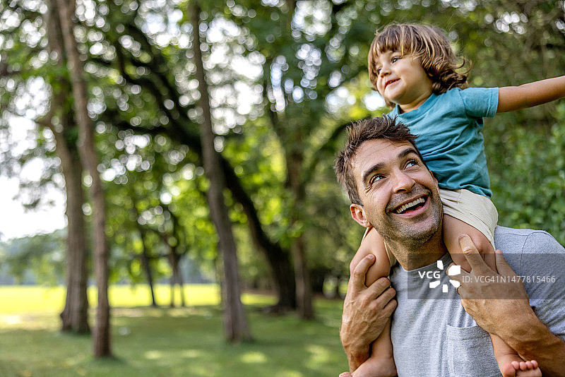 快乐的父亲在公园里把儿子扛在肩上图片素材