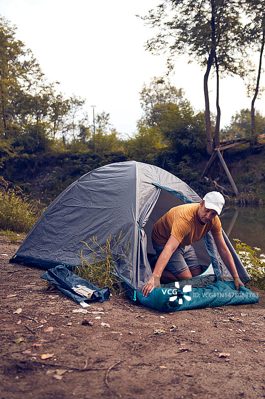人们在大自然中露营，在森林河附近搭起帐篷过夜。图片素材