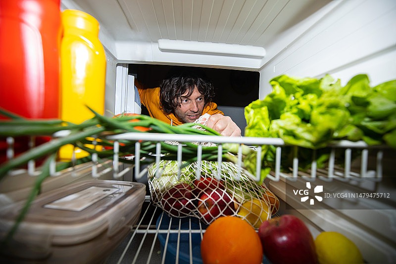 一个人把蔬菜放进冰箱，可持续发展的概念图片素材