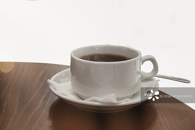 在舒适的咖啡馆里。卡布奇诺加奶油泡沫在白色陶瓷杯上的碟子。带有复制空间的天然热饮特写。图片素材
