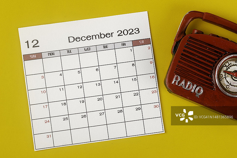 2023日历台:12月是组织者计划和截止日期的月份，背景是黄色纸张的老式收音机。图片素材