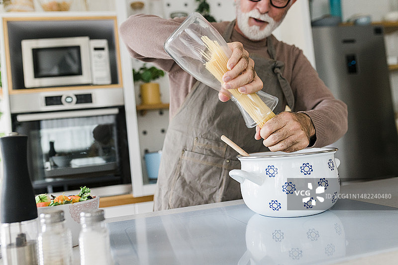 特写快乐的老人站在厨房柜台和烹饪美味的健康餐在炉子上图片素材