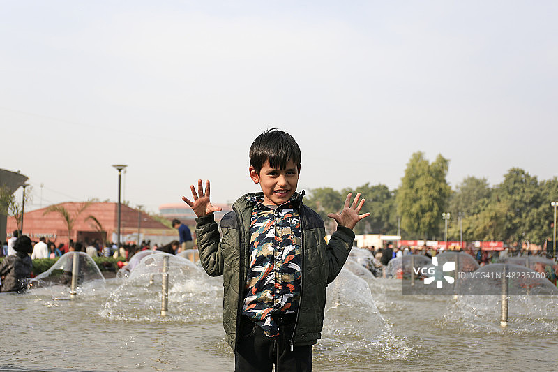 快乐的孩子站在喷泉旁的肖像图片素材