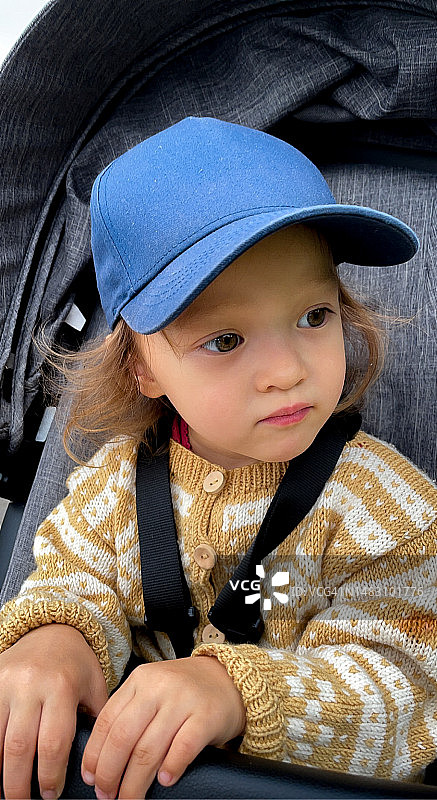 一个戴着帽子穿着针织夹克的孩子。图片素材