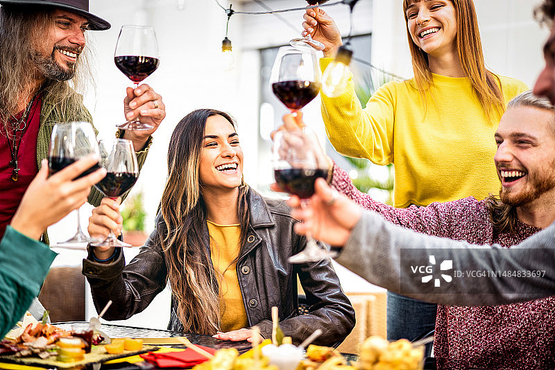时髦的人在家里的酒吧花园享受红酒的乐趣-快乐的朋友在露天餐厅用餐时分享真正的时间-温暖的生动过滤器上的饮料生活方式概念图片素材