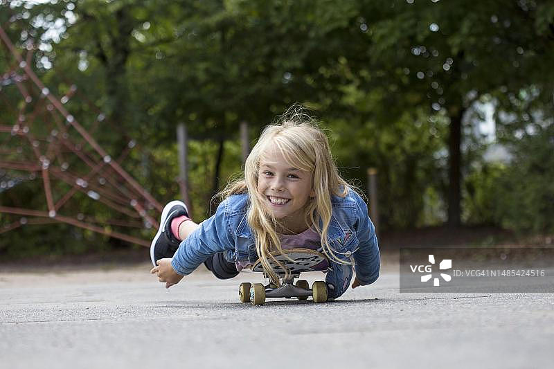 德国石勒苏益格-荷尔斯泰因州基尔，躺在滑板上的女孩(10岁)图片素材