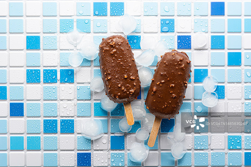 在俄罗斯，一块蓝白相间的瓷砖上，雪糕上涂着巧克力坚果釉，平铺着爱斯基摩冰棒图片素材