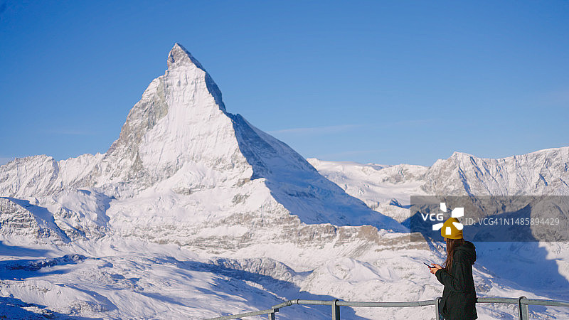 年轻女子在瑞士马特洪峰山顶使用电话。图片素材