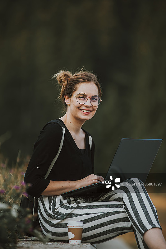 年轻女性自由职业者在户外用笔记本电脑工作，波斯尼亚和黑塞哥维那图片素材