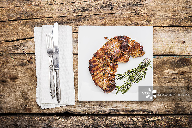 烤牛排与迷迭香束装饰在白色盘子餐厅菜单或食谱背景俯视图图像，罗马尼亚图片素材
